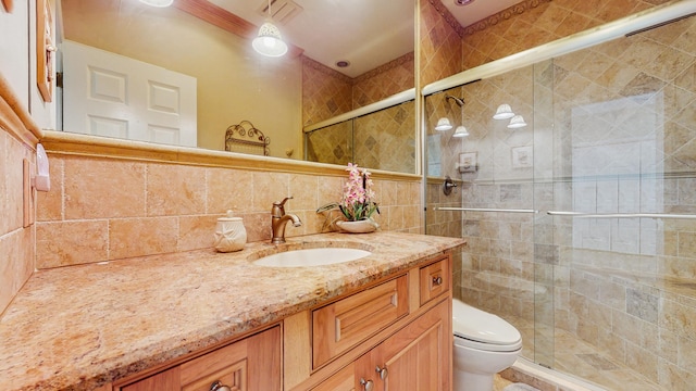 bathroom featuring visible vents, toilet, vanity, a shower stall, and tile walls