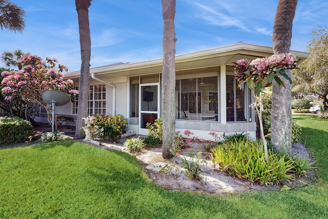 view of front facade with a front yard and a sunroom