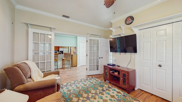 living area with visible vents, ornamental molding, wood finished floors, and french doors