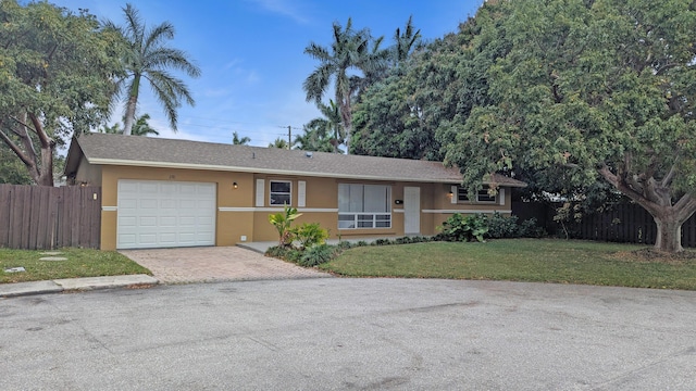 ranch-style home featuring stucco siding, decorative driveway, a front yard, and fence