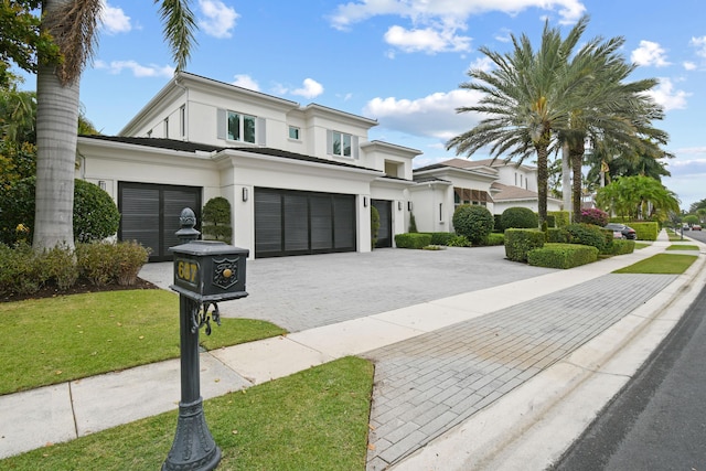 view of front of property featuring a garage, a front lawn, decorative driveway, and stucco siding