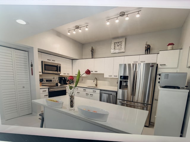 kitchen with appliances with stainless steel finishes, light countertops, white cabinets, and a sink