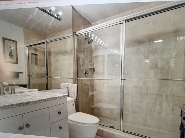 full bath featuring a stall shower, vanity, and toilet