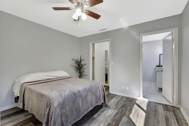 bedroom with a ceiling fan, visible vents, baseboards, and wood finished floors