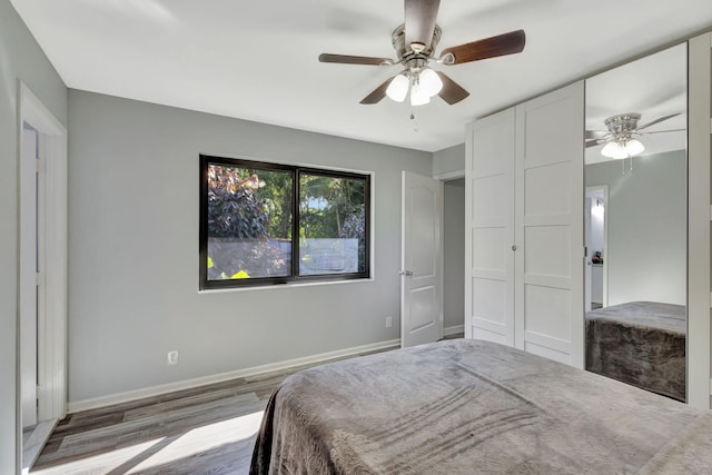 bedroom featuring a ceiling fan, baseboards, and wood finished floors