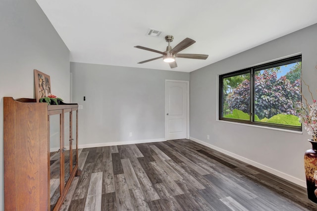 spare room with baseboards, visible vents, ceiling fan, and dark wood-type flooring