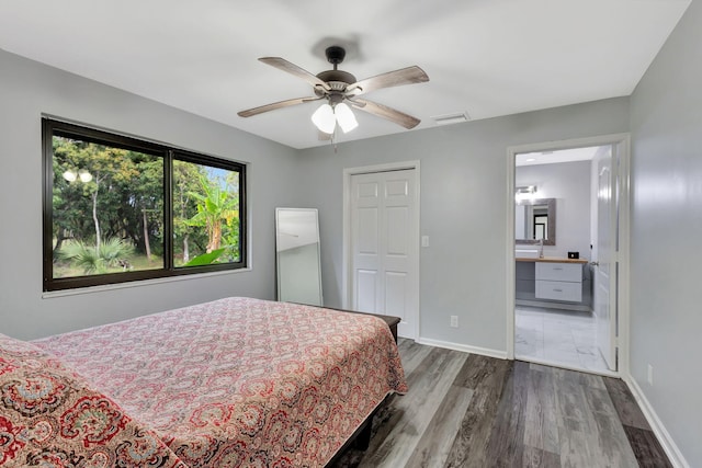 bedroom featuring connected bathroom, wood finished floors, a ceiling fan, visible vents, and baseboards