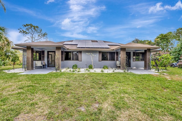 back of property featuring a lawn, a patio, and solar panels