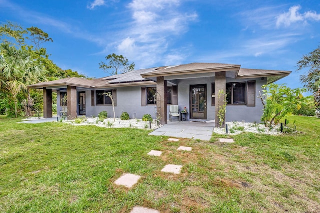 prairie-style home with a porch, solar panels, a front lawn, and stucco siding