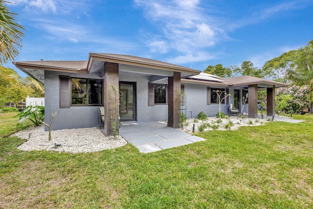 back of property with a patio area, a lawn, and stucco siding