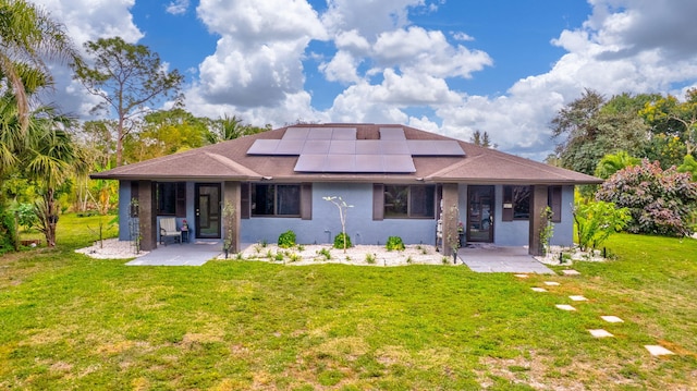 back of property with roof mounted solar panels, stucco siding, a yard, and a patio