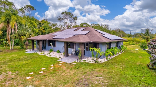 ranch-style home with a patio area, a front lawn, solar panels, and stucco siding