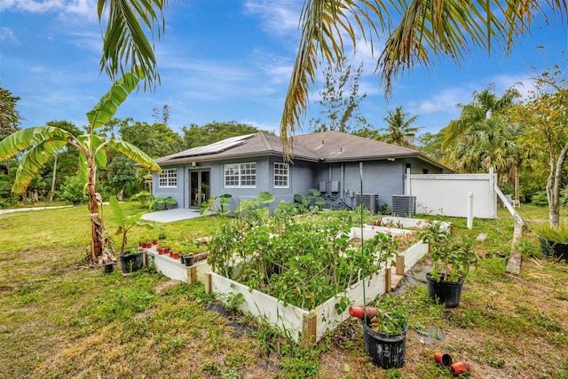 back of house with a yard, a patio, a vegetable garden, and stucco siding