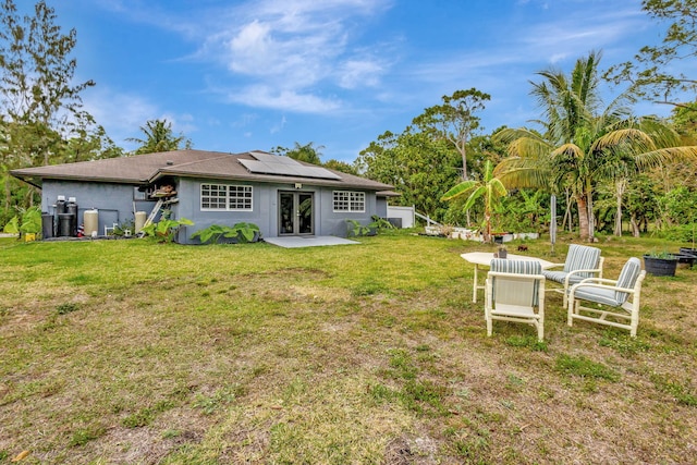 rear view of house with a yard and solar panels