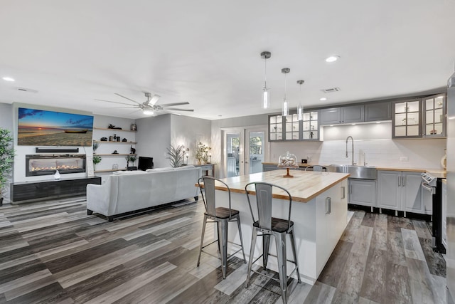 kitchen featuring a sink, open floor plan, stainless steel electric stove, a glass covered fireplace, and glass insert cabinets