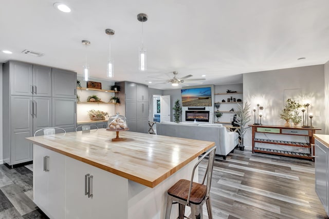 kitchen featuring visible vents, a glass covered fireplace, butcher block countertops, wood finished floors, and gray cabinets