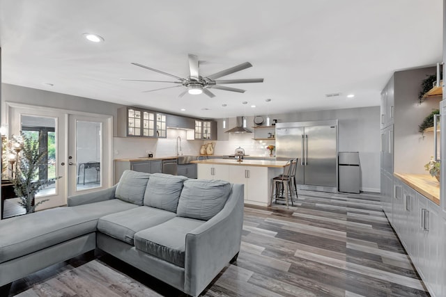 living area with a wealth of natural light, wood finished floors, ceiling fan, and recessed lighting