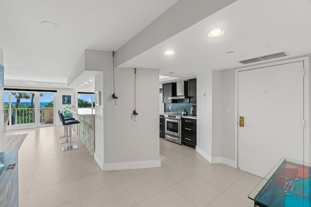 kitchen with visible vents, electric range, decorative backsplash, wall chimney range hood, and dark cabinetry