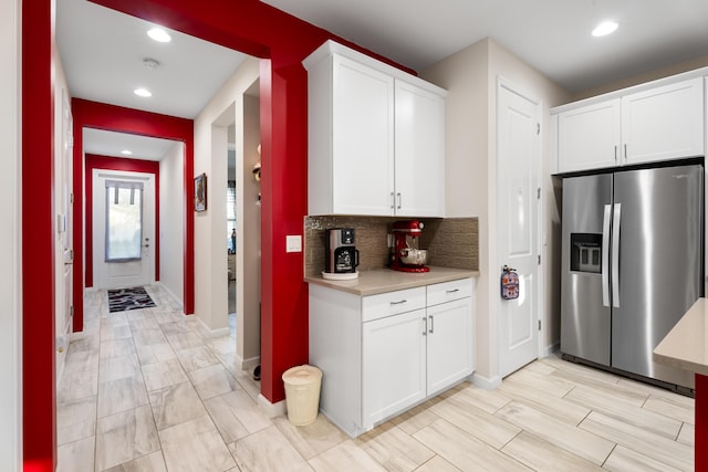 kitchen with recessed lighting, white cabinetry, light countertops, stainless steel refrigerator with ice dispenser, and backsplash