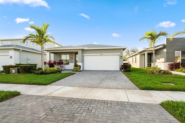 view of front of house with a front yard, decorative driveway, an attached garage, and stucco siding