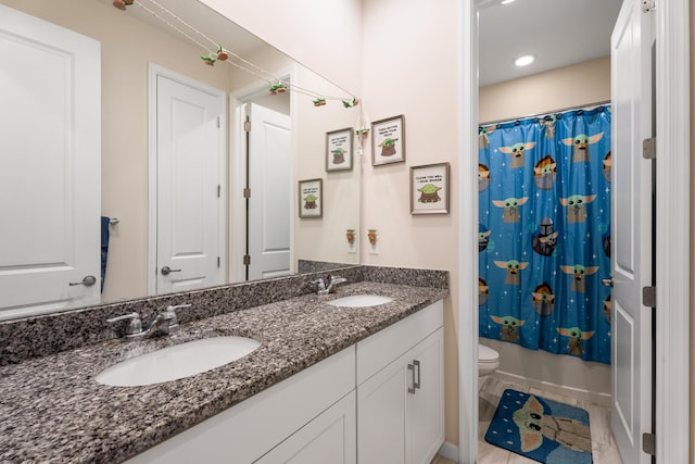 full bath featuring double vanity, a shower with curtain, toilet, and a sink