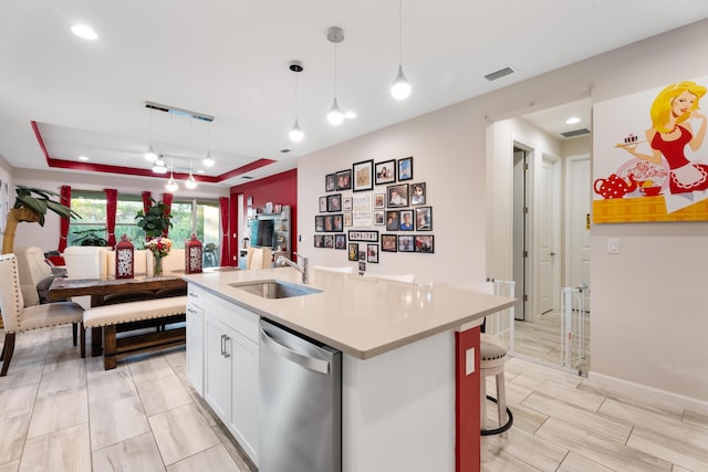 kitchen with a sink, open floor plan, hanging light fixtures, stainless steel dishwasher, and a center island with sink