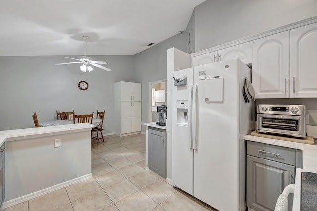 kitchen with light countertops, white fridge with ice dispenser, gray cabinets, and white cabinets