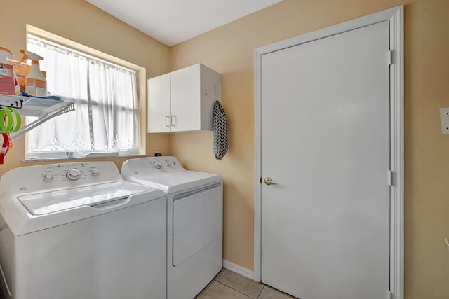 clothes washing area featuring cabinet space, washer and clothes dryer, and light tile patterned flooring