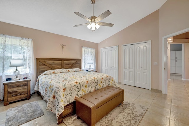 bedroom with lofted ceiling, light tile patterned floors, multiple windows, and two closets