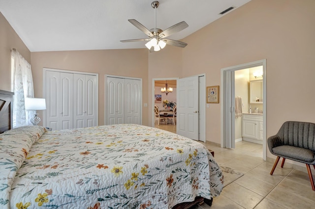 bedroom featuring visible vents, ensuite bathroom, light tile patterned flooring, multiple closets, and ceiling fan with notable chandelier