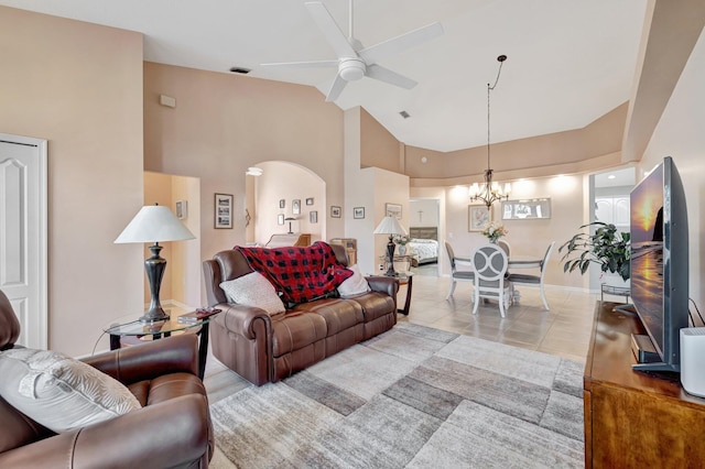 living room featuring visible vents, arched walkways, light tile patterned flooring, high vaulted ceiling, and ceiling fan with notable chandelier