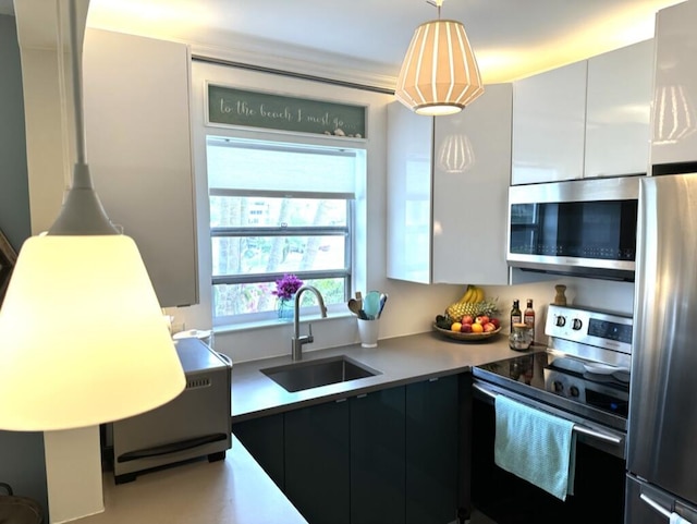 kitchen with stainless steel appliances, light countertops, hanging light fixtures, a sink, and modern cabinets