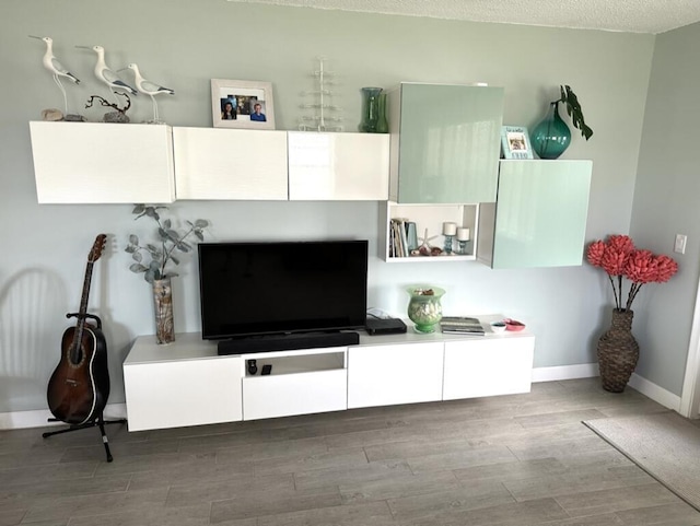 living room with a textured ceiling, wood finished floors, and baseboards