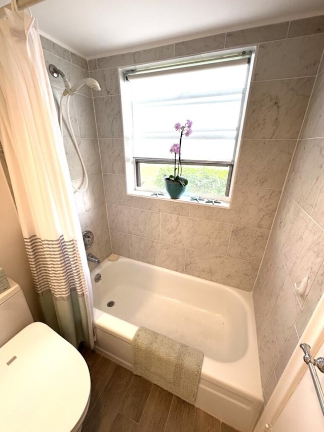 bathroom with shower / tub combo, toilet, and wood finished floors