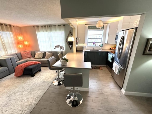 kitchen with a breakfast bar area, stainless steel appliances, open floor plan, a sink, and modern cabinets