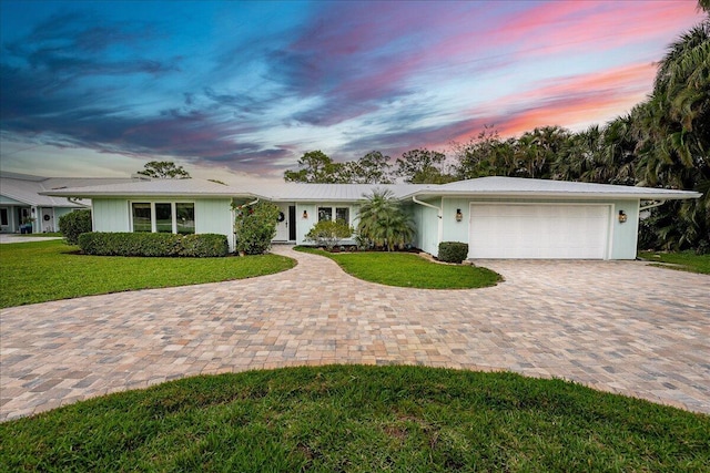 single story home featuring a garage, decorative driveway, and a front yard