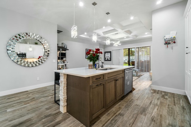 kitchen featuring light countertops, appliances with stainless steel finishes, a kitchen island with sink, a sink, and coffered ceiling