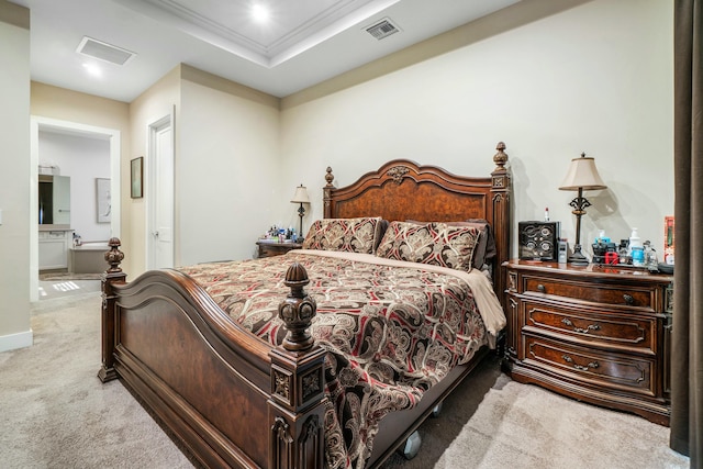 carpeted bedroom with a tray ceiling, visible vents, crown molding, and ensuite bath