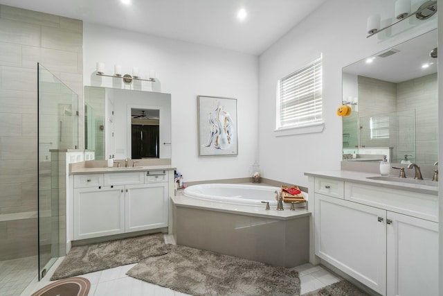 bathroom featuring a stall shower, two vanities, a sink, and a garden tub