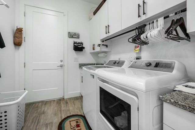 laundry area with cabinet space, light wood finished floors, and washing machine and clothes dryer