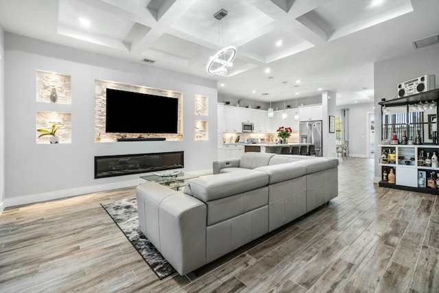 living room with coffered ceiling, visible vents, baseboards, light wood-style floors, and beam ceiling