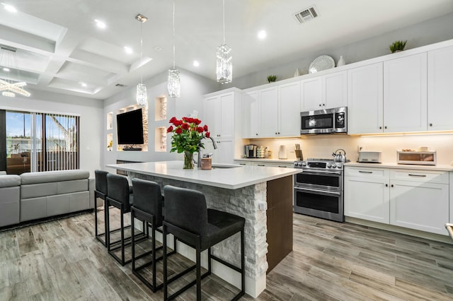 kitchen with a center island, stainless steel appliances, light countertops, open floor plan, and white cabinetry