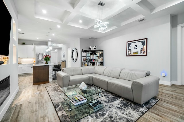 living area with light wood-style floors, visible vents, and an inviting chandelier