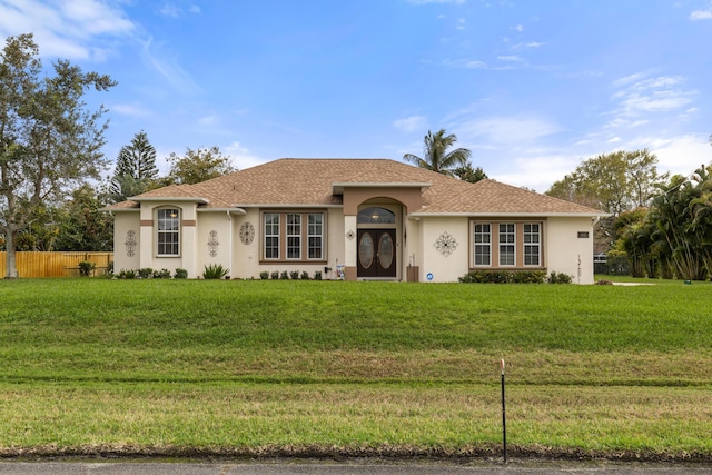 ranch-style home with stucco siding, fence, and a front yard