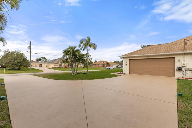 exterior space featuring a residential view, concrete driveway, a front lawn, and stucco siding