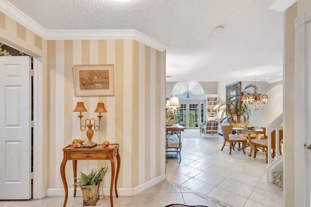 corridor featuring a textured ceiling, a notable chandelier, baseboards, ornamental molding, and wallpapered walls