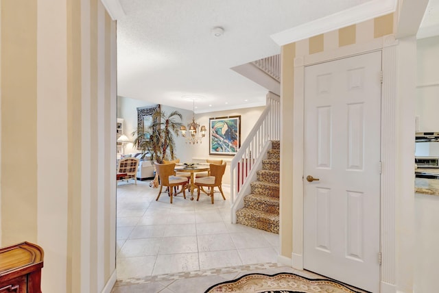 interior space featuring light tile patterned flooring, baseboards, stairway, an inviting chandelier, and crown molding