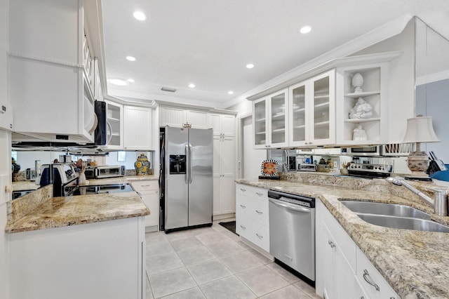 kitchen featuring light stone counters, stainless steel appliances, a sink, white cabinetry, and glass insert cabinets