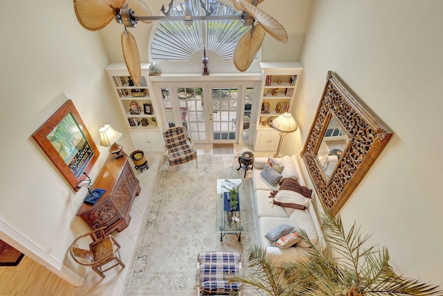 living area with baseboards, french doors, a high ceiling, and built in features