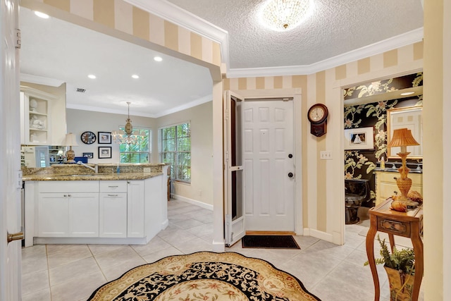 entrance foyer featuring a textured ceiling, ornamental molding, baseboards, and wallpapered walls